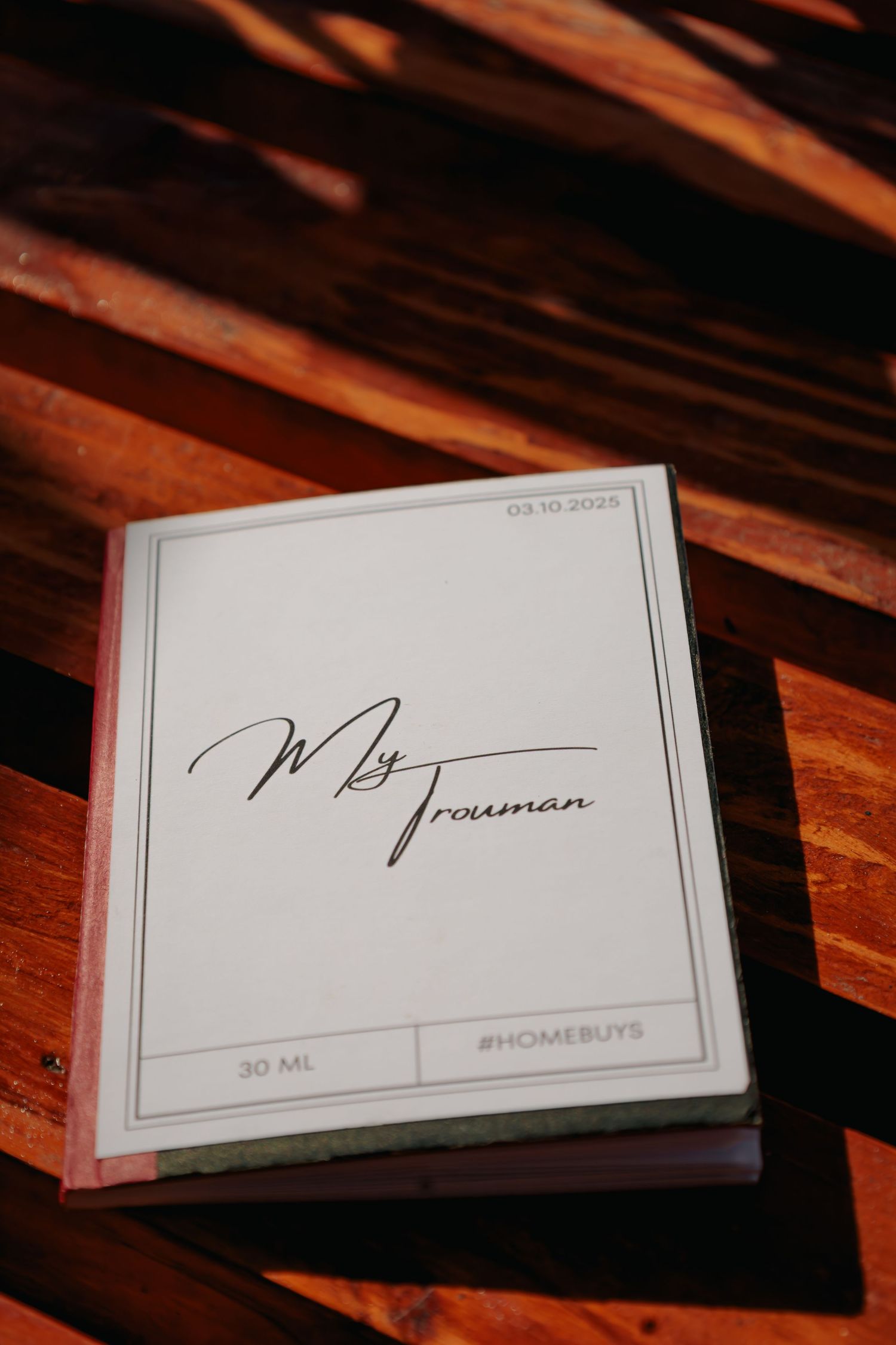 Custom wedding vow book labeled My Trouman dated 03.10.2025 on wooden surface.