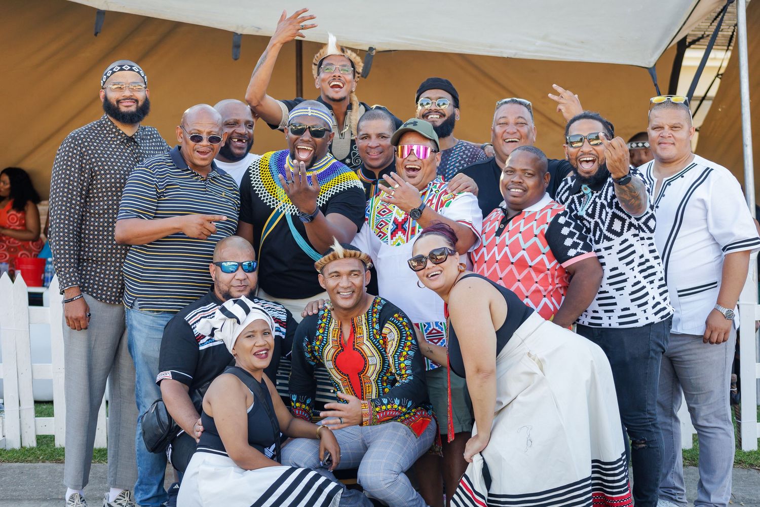 Large group of wedding guests in colorful traditional Xhosa attire posing together for a festive photo.