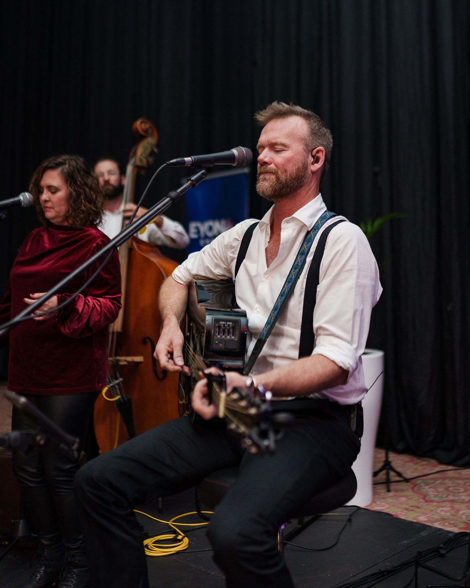Male guitarist performing with band at Beyond Energy corporate event on stage.