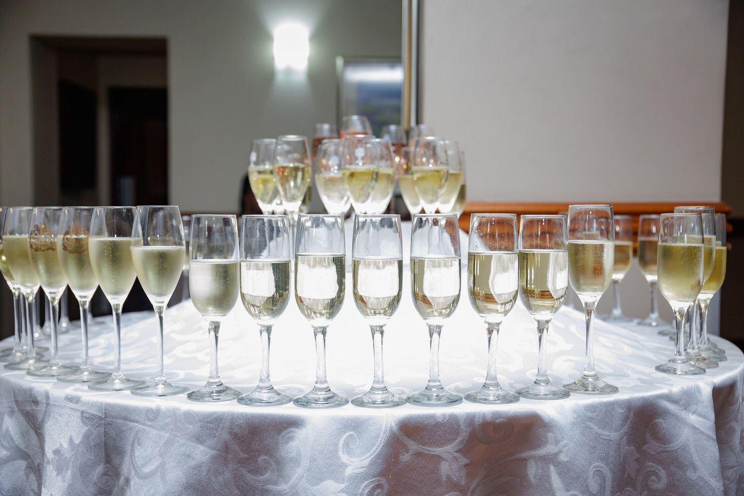 Multiple champagne glasses arranged on a round table at a formal event.