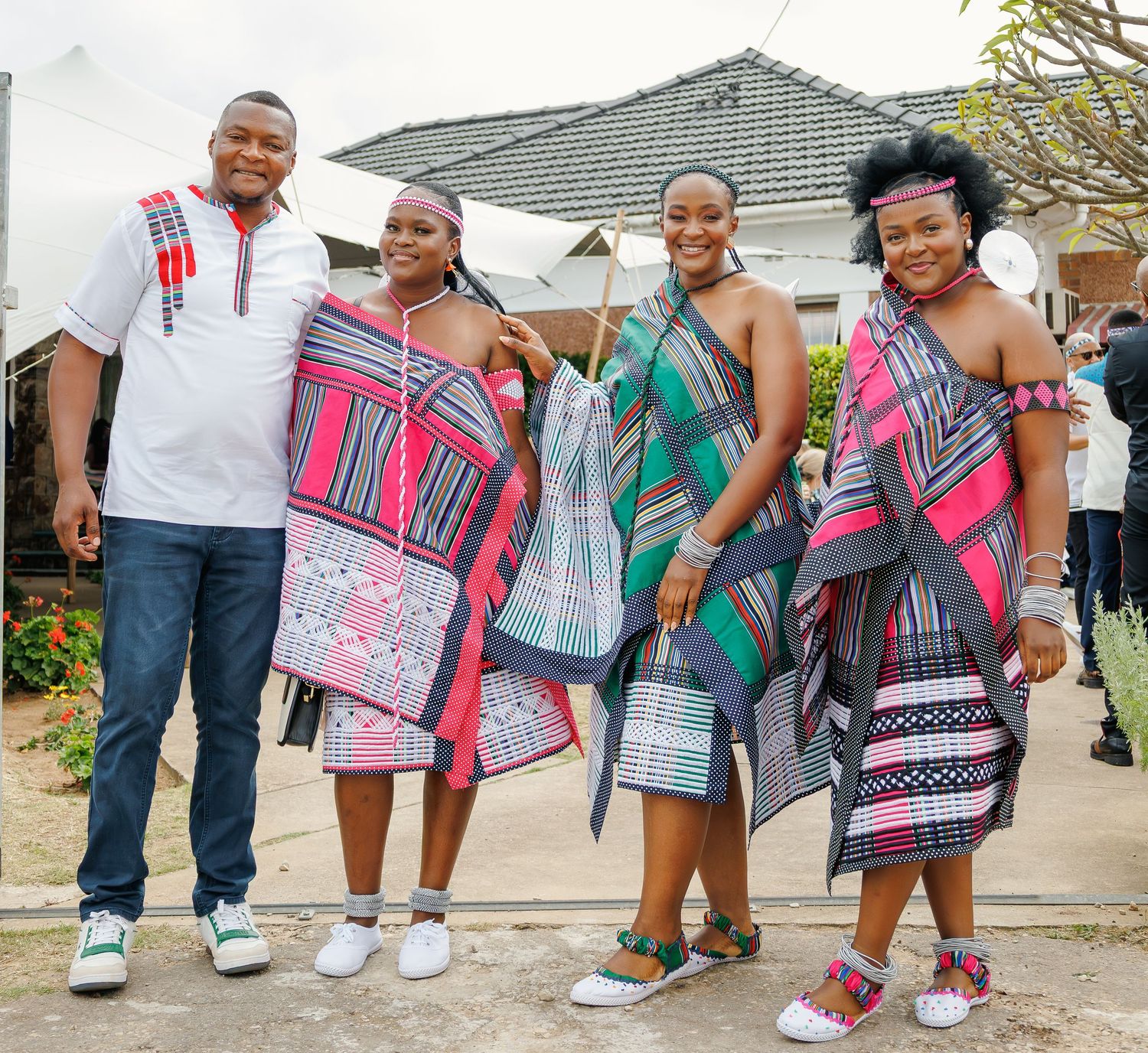 Family of four proudly wearing matching colorful traditional Sotho blanket attire at outdoor gathering.