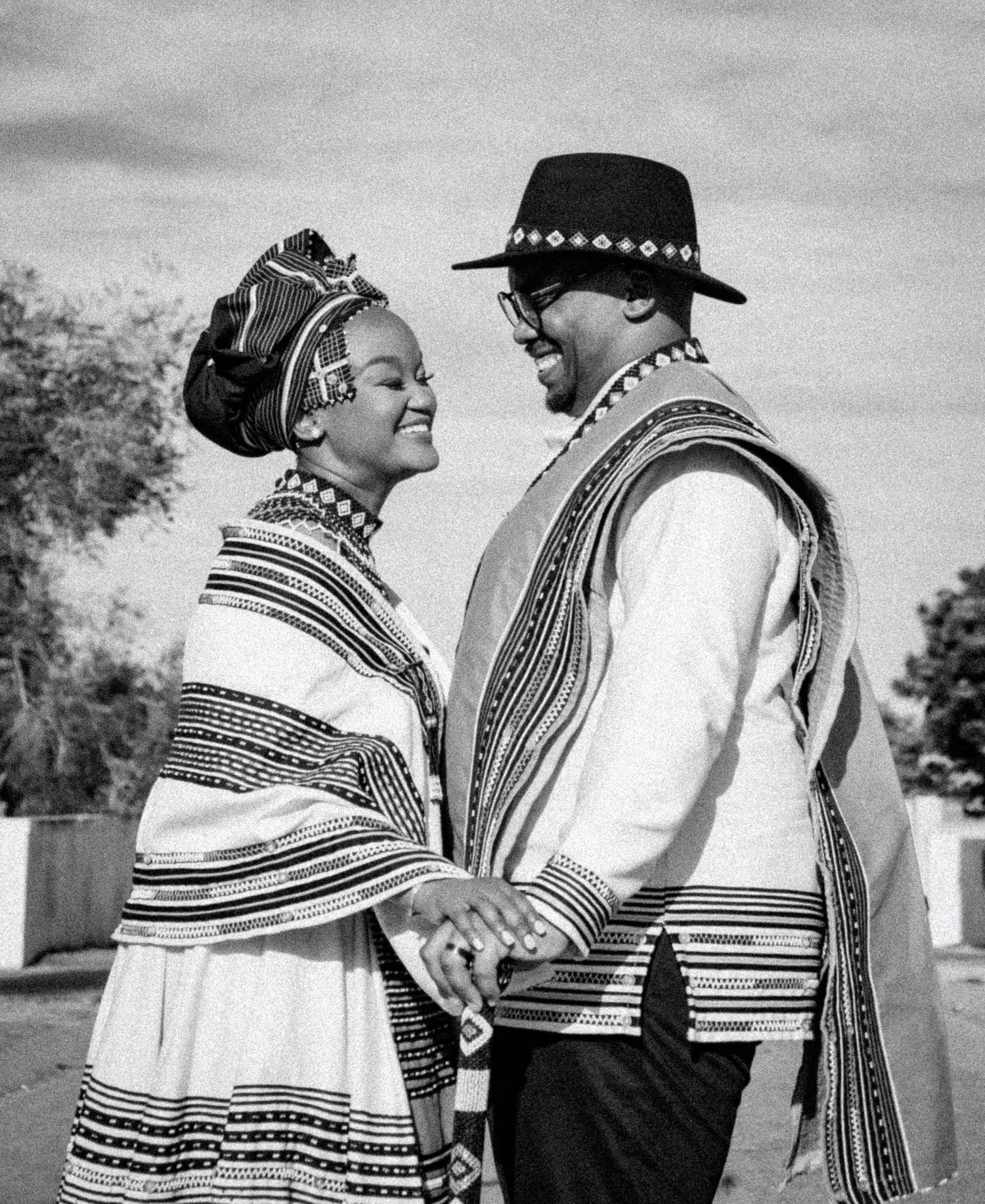Black and white portrait of a couple in traditional Xhosa attire gazing at each other.