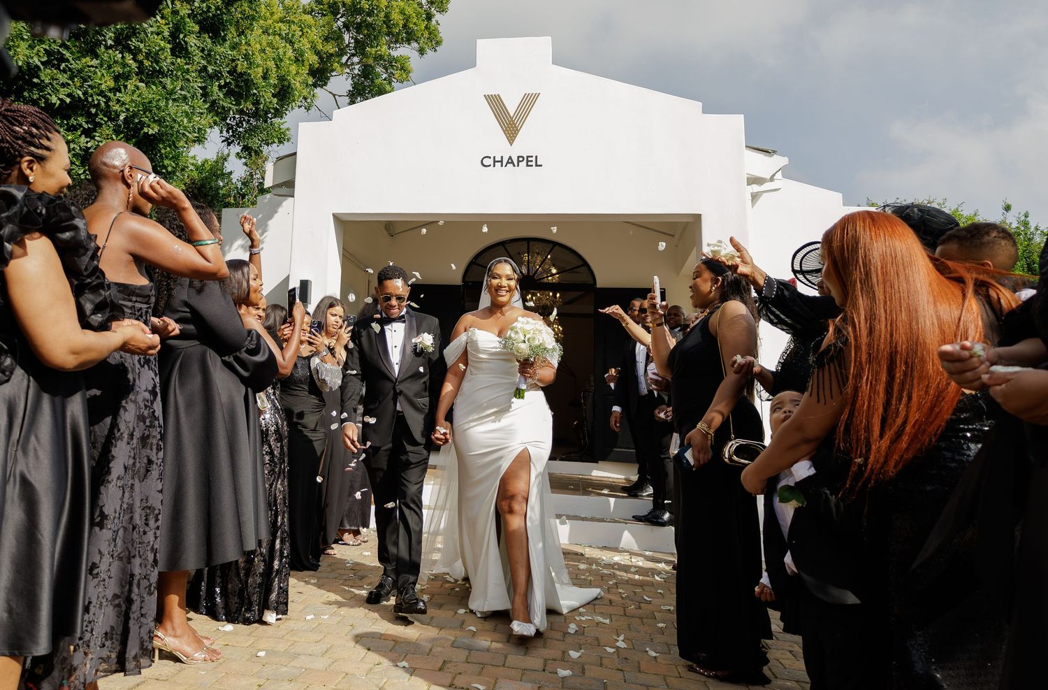 Bride and groom exit V Chapel surrounded by celebrating guests in black attire.