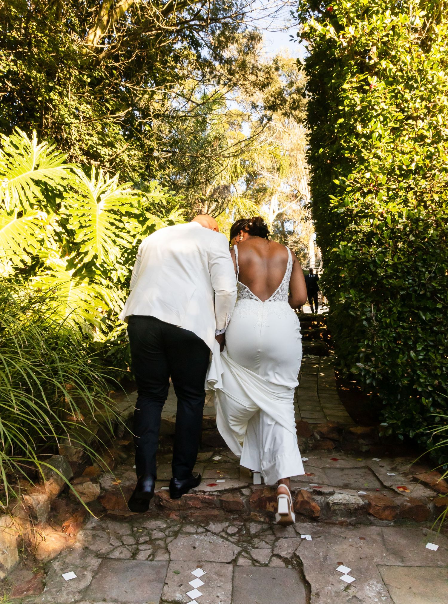 Bride and groom walking hand in hand through a lush garden pathway after ceremony.