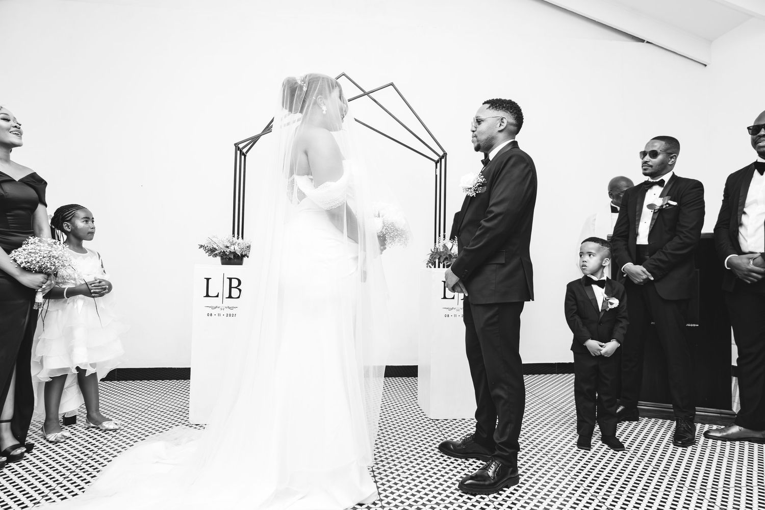 Bride and groom stand at altar during wedding ceremony with ring bearer and flower girl.