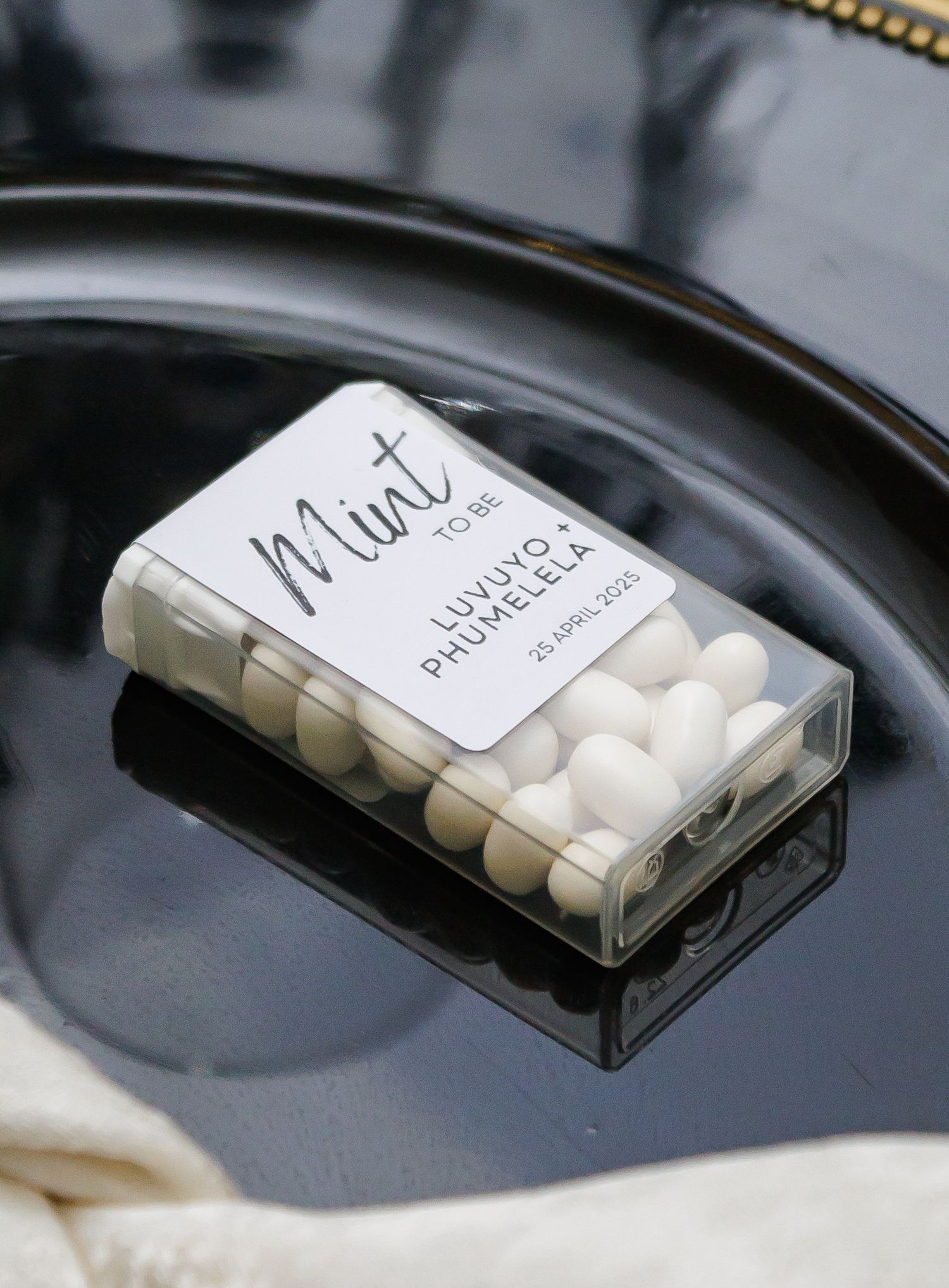 Mint to Be wedding favor tic-tac box personalized for Luvuyo and Phumelela on black plate.