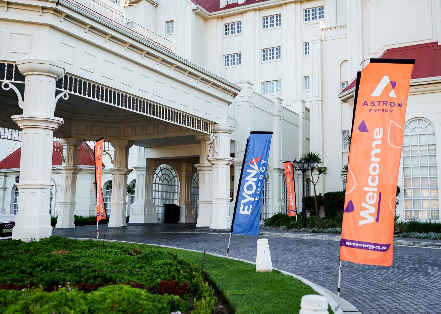 Astron Energy and Eyona Energy welcome banners displayed outside a grand white building entrance.