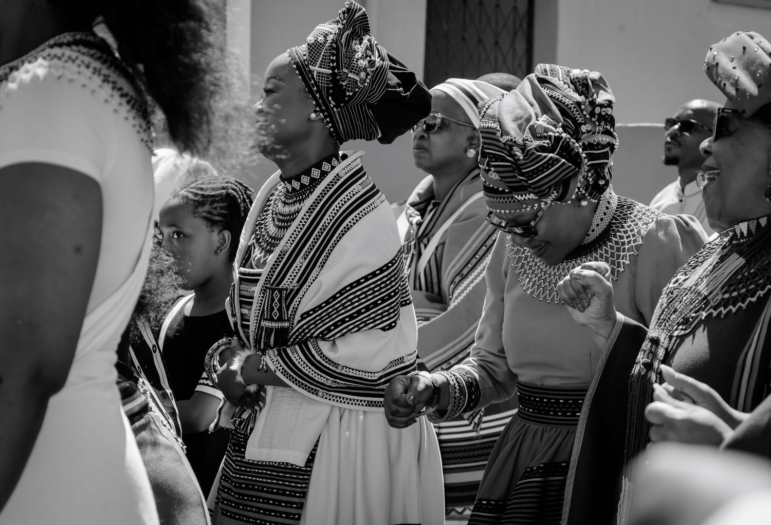 Black and white photo of women in traditional Xhosa beaded attire gathered at a cultural ceremony.