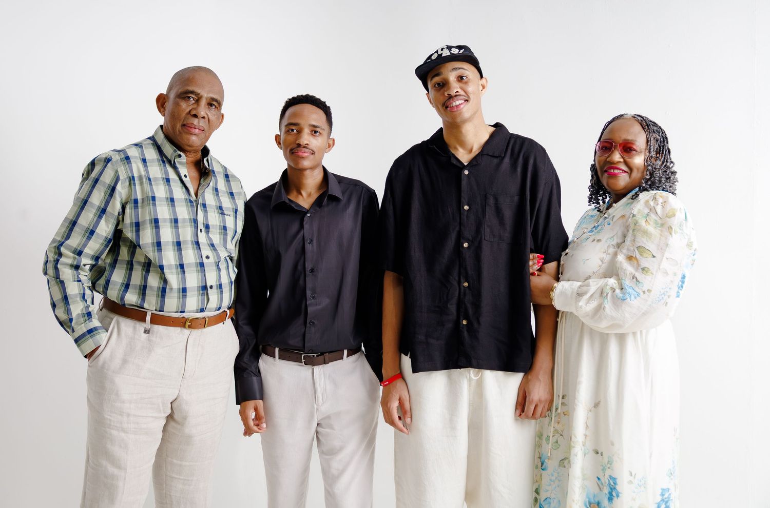 Family of four posing together smiling, wearing casual clothing against a white studio background.