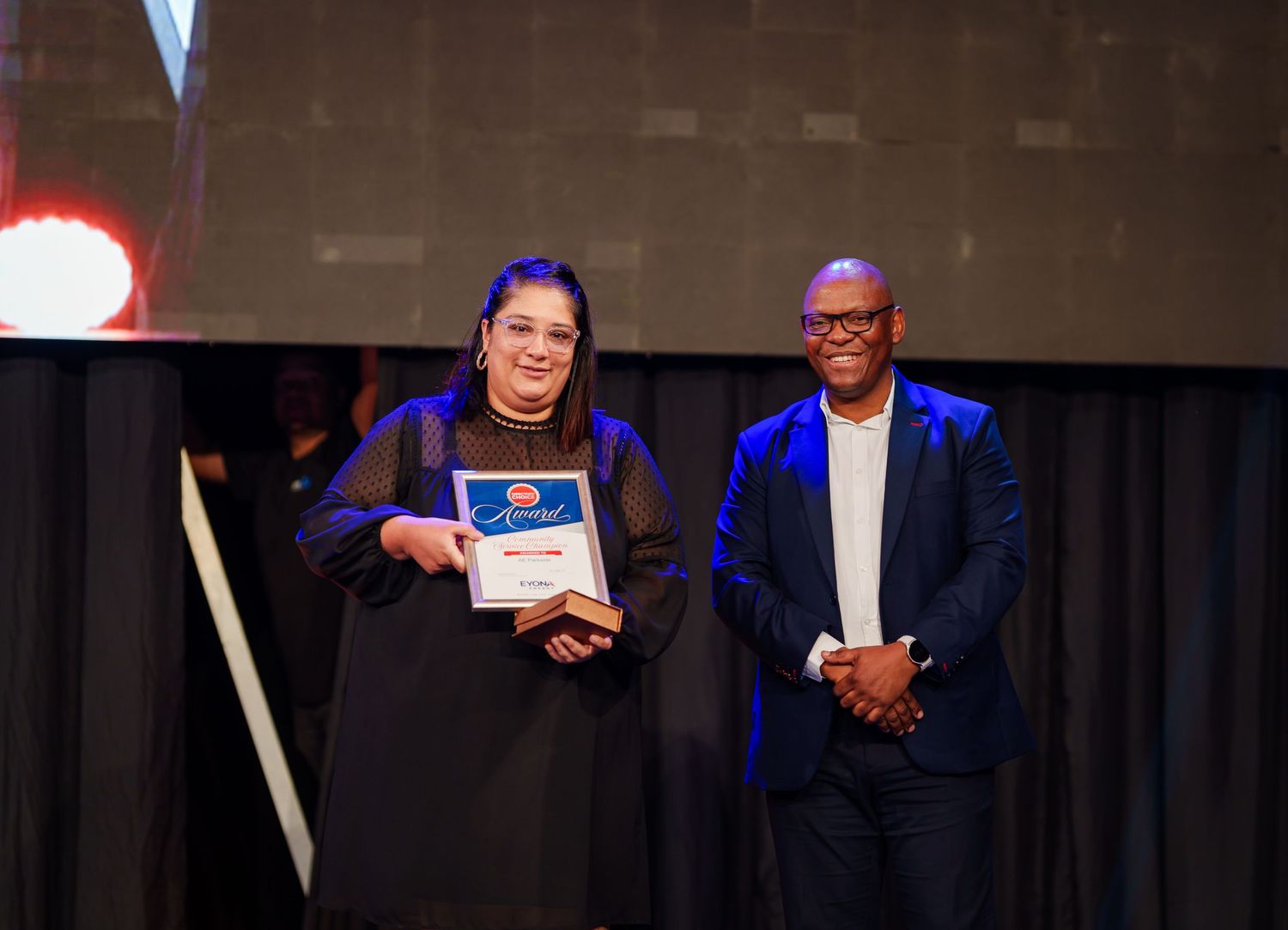 Woman receives certificate award on stage at formal corporate recognition ceremony.
