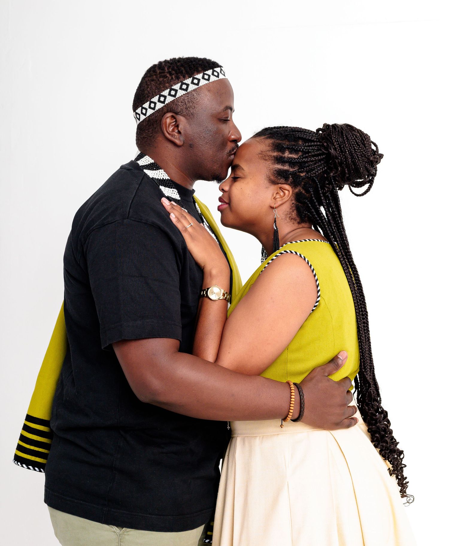 Couple sharing a romantic kiss wearing traditional African Xhosa cultural attire in white studio.