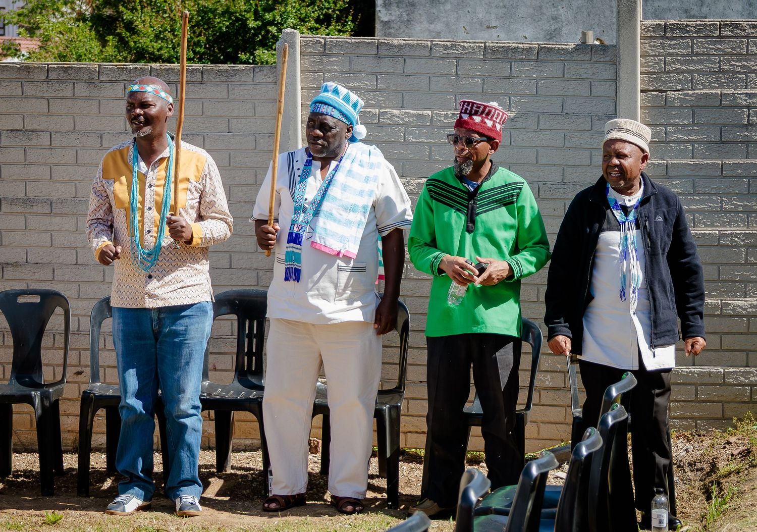 Four men in colorful traditional African attire stand together outdoors at a cultural celebration.