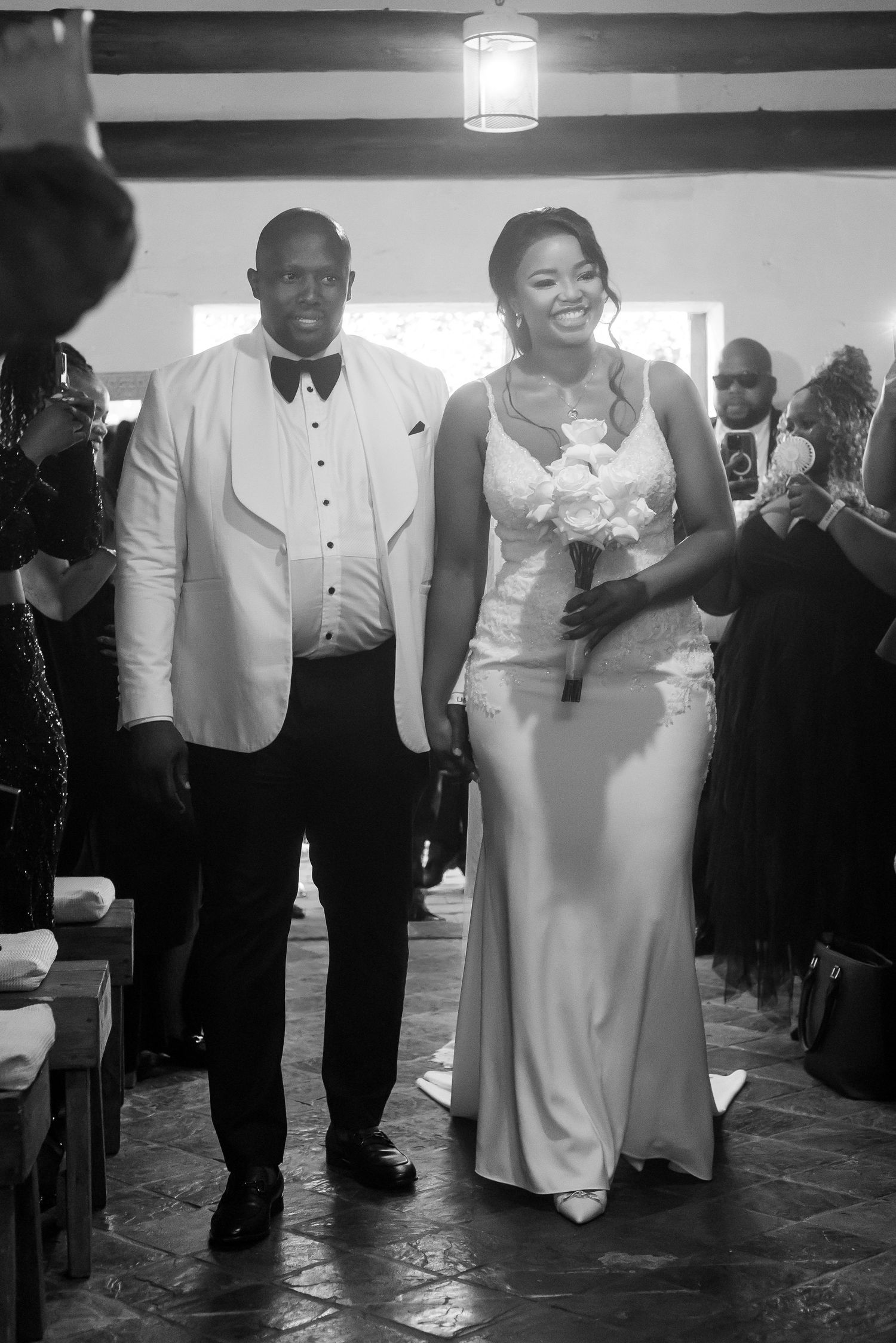 Smiling bride walking down the aisle with her escort in a rustic chapel interior.