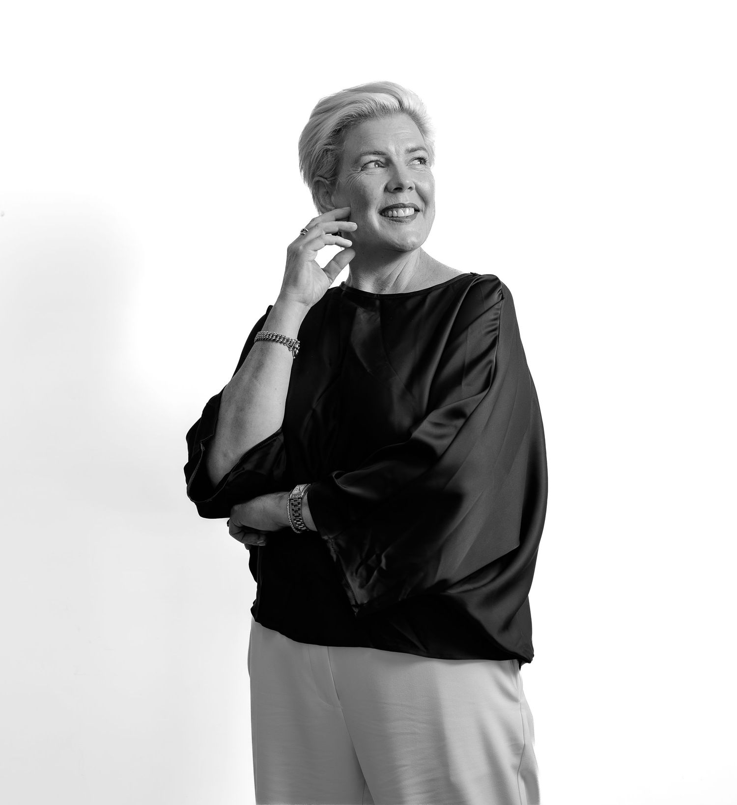 Elegant woman in black top poses thoughtfully in black and white portrait.