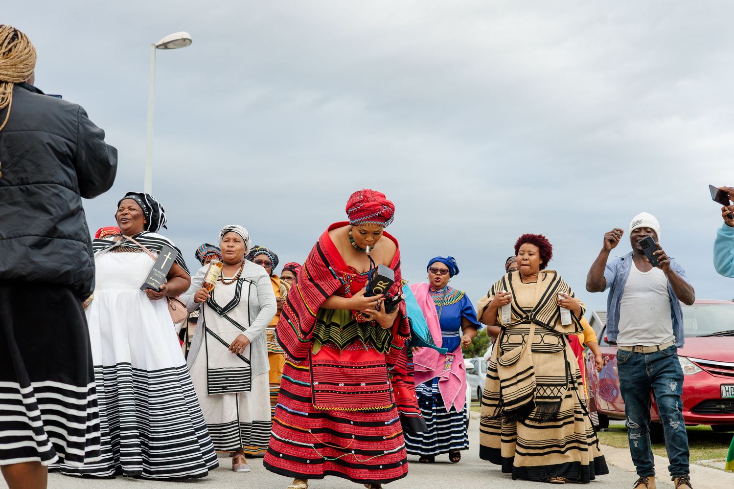 Colorful traditional African cultural celebration with women in vibrant traditional attire dancing outdoors.