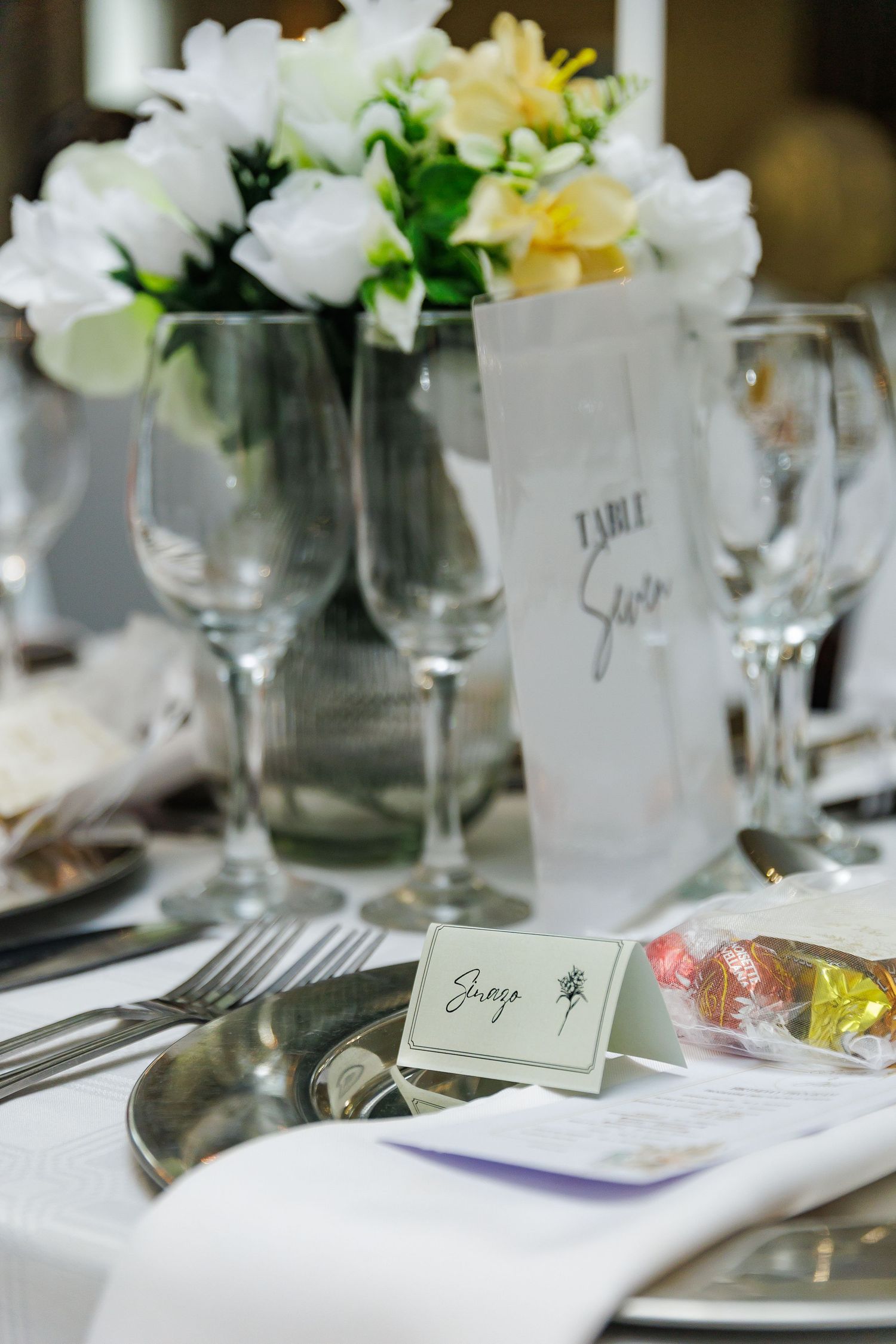 Formal table setting with white flowers, wine glasses, and personalized place cards.
