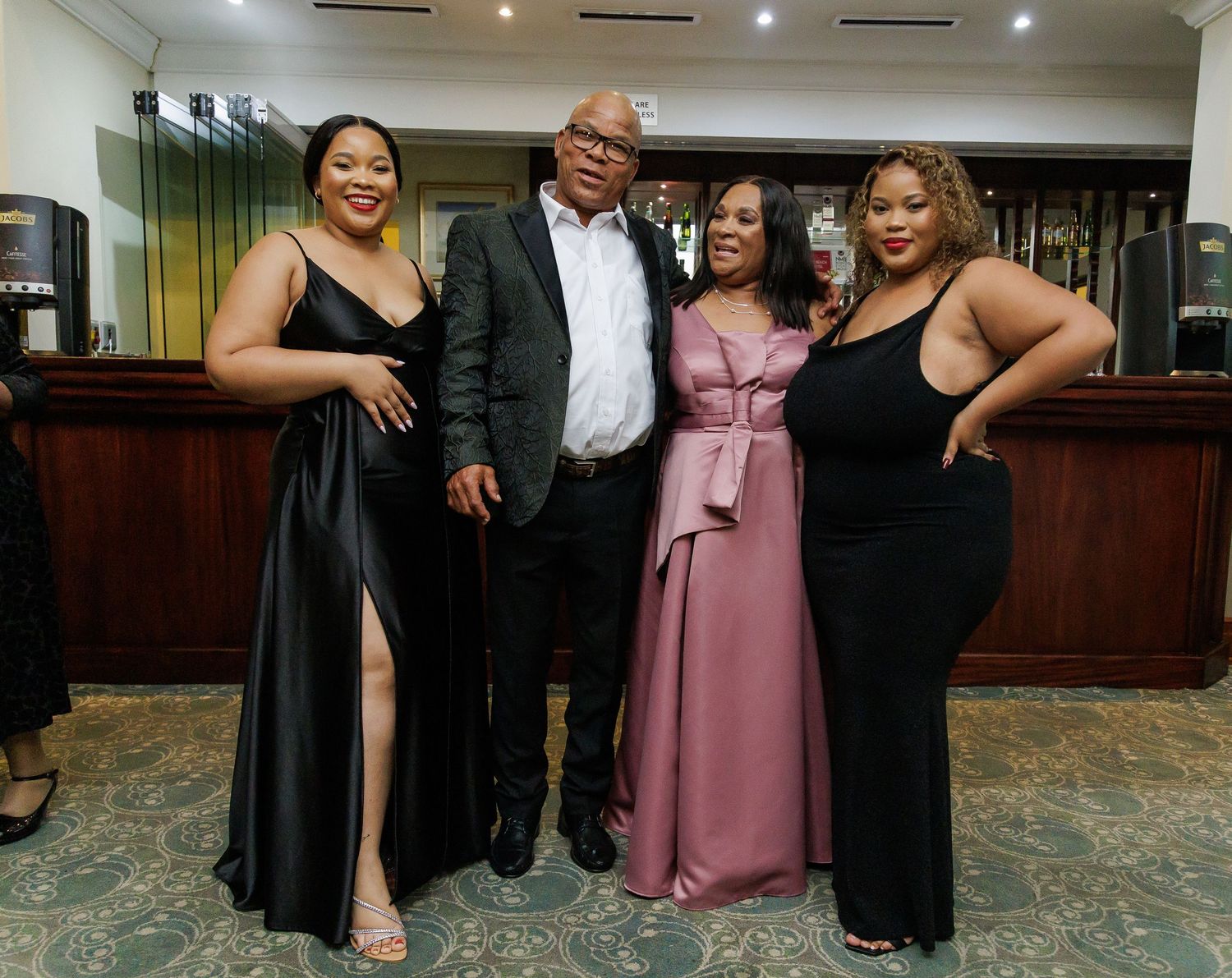 Family of four posing together and smiling at an elegant indoor celebration.