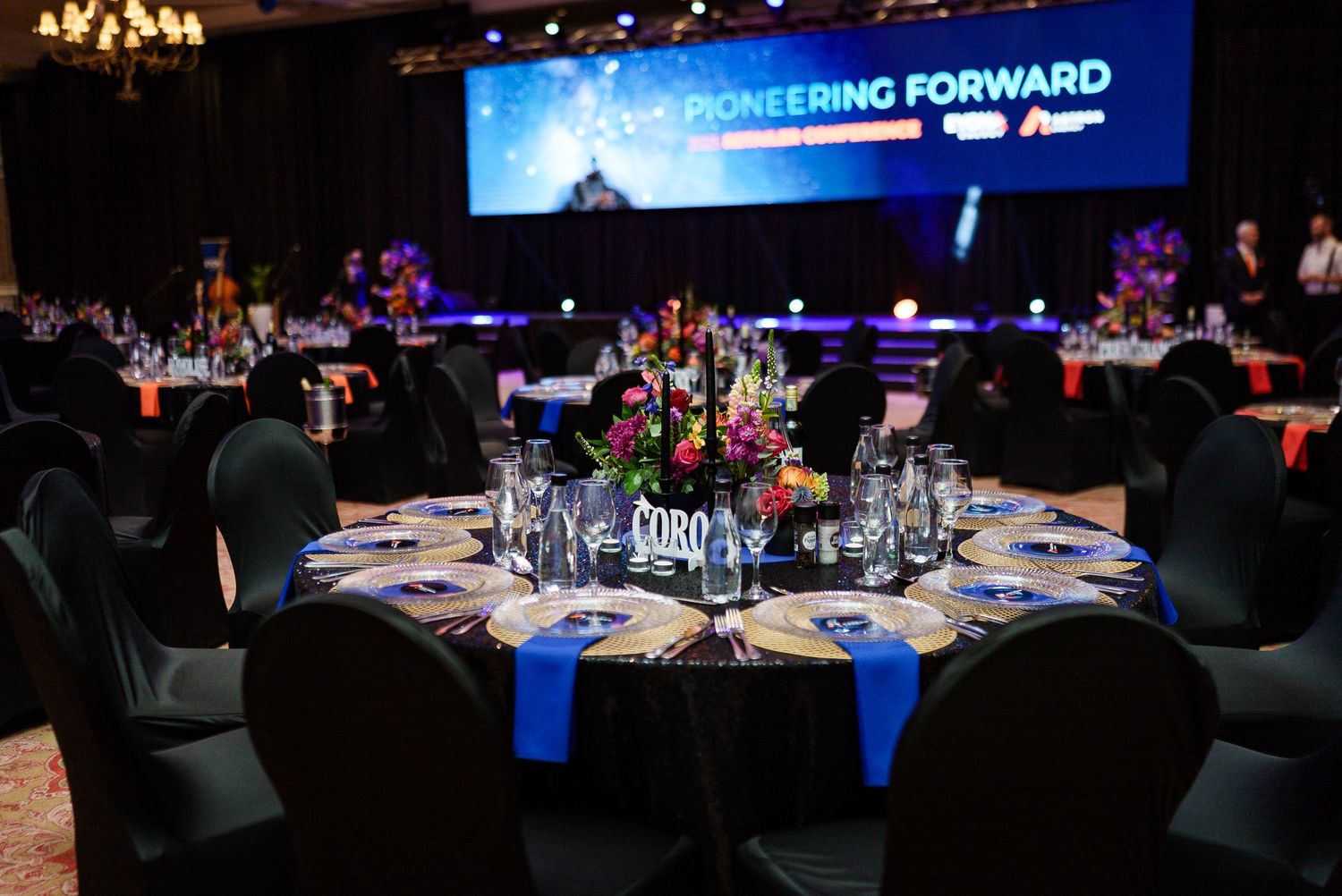 Elegant banquet hall setup with round tables for Pioneering Forward conference gala dinner.