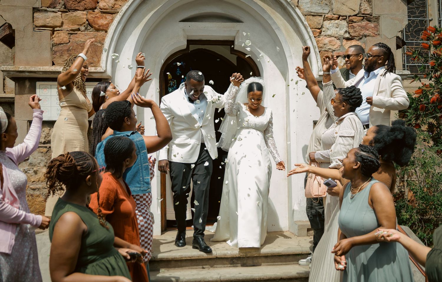Joyful bride and groom exit church as guests celebrate with confetti shower.