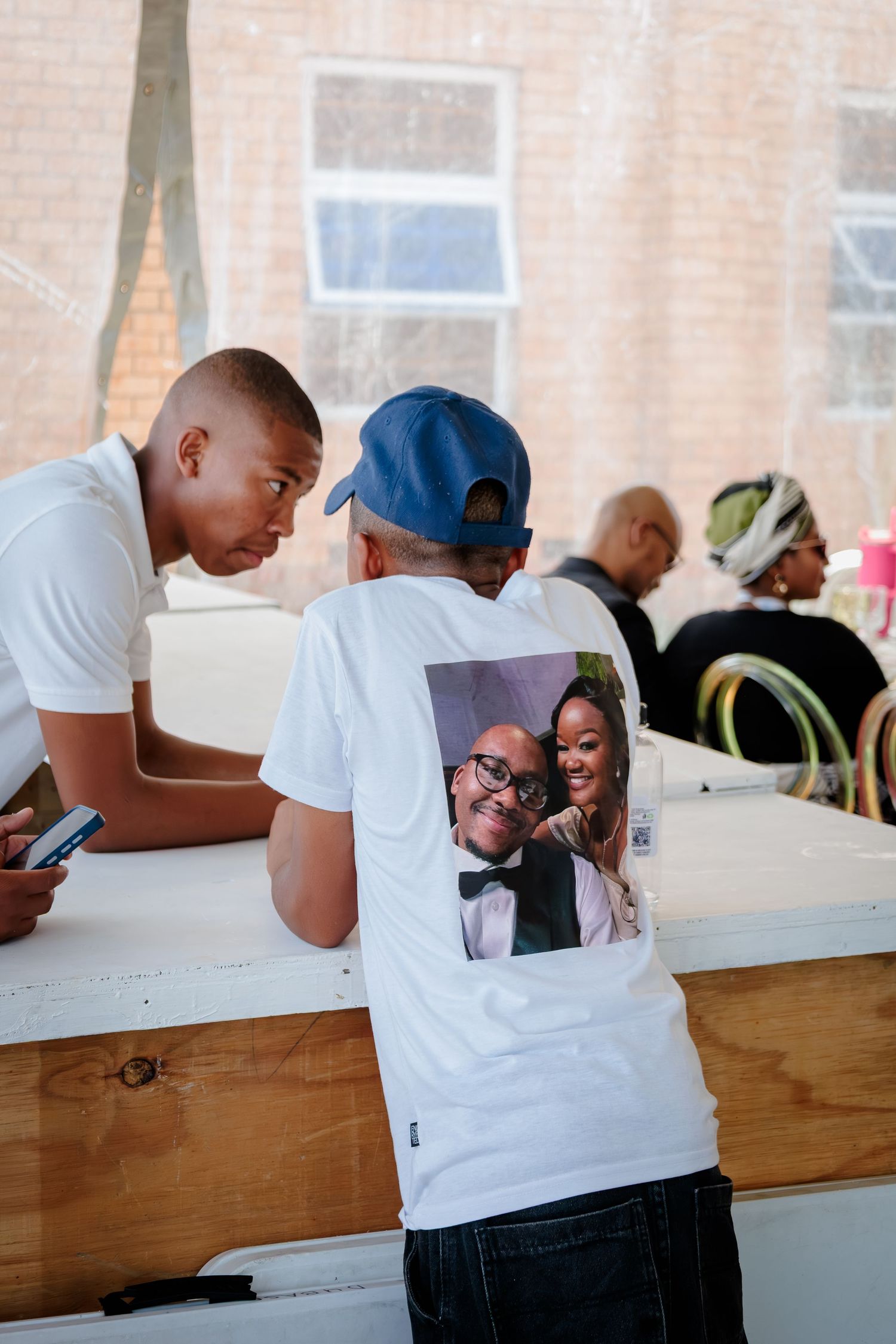 Young man wearing a custom photo t-shirt at a traditional African wedding celebration.