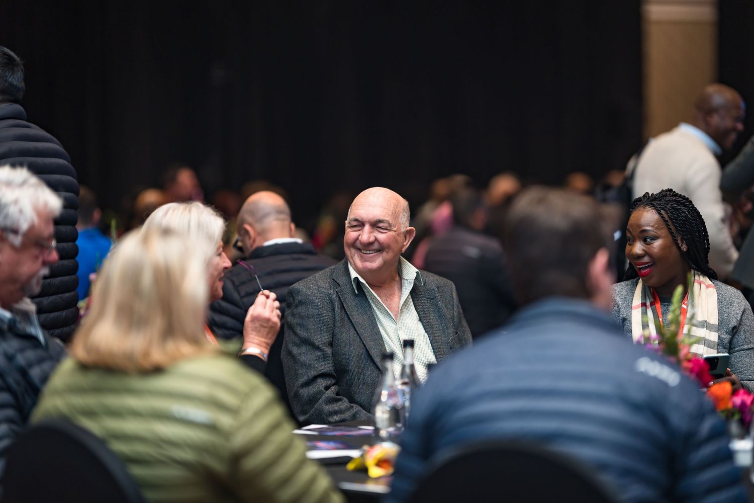 Smiling bald man engages with colleagues at a business networking dinner event.