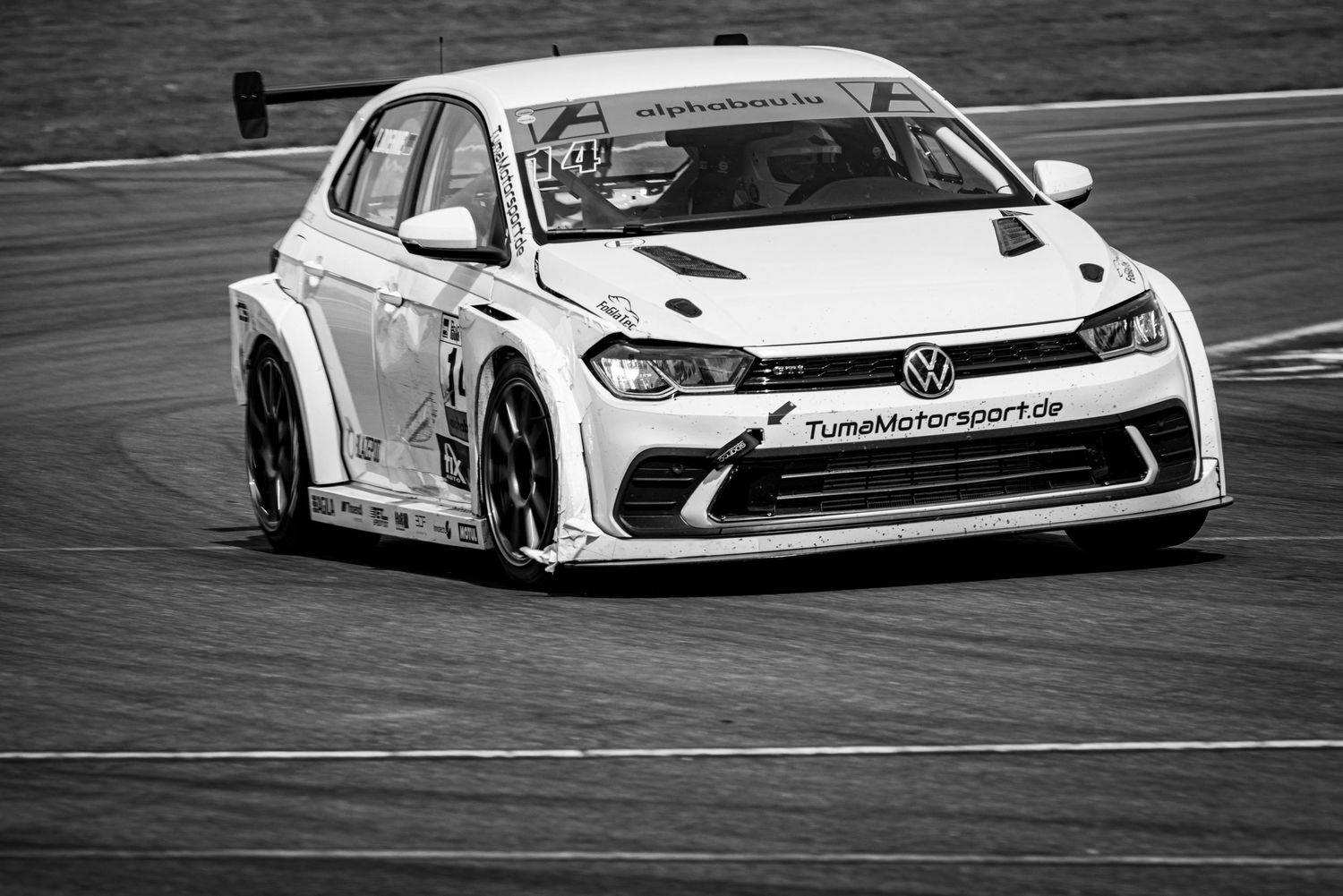 Black and white photo of a Volkswagen Polo TCR race car on track with TunaMotorsport.de livery.