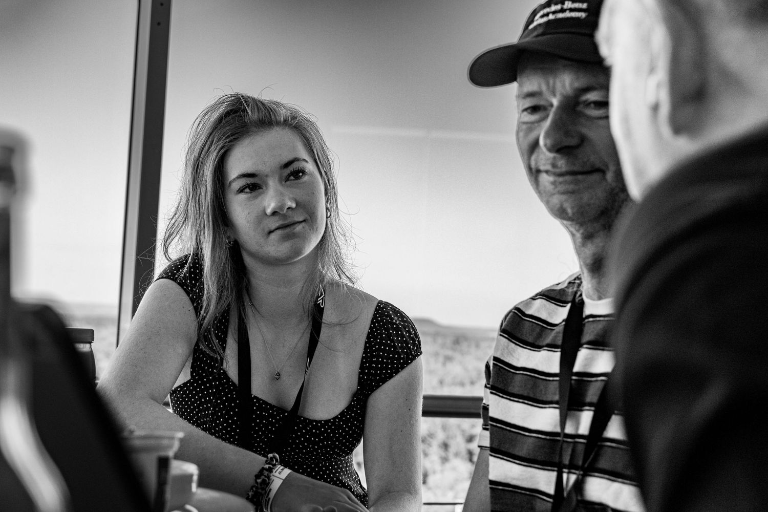Black and white photo of a young woman and older man in a striped shirt having a conversation outdoors.