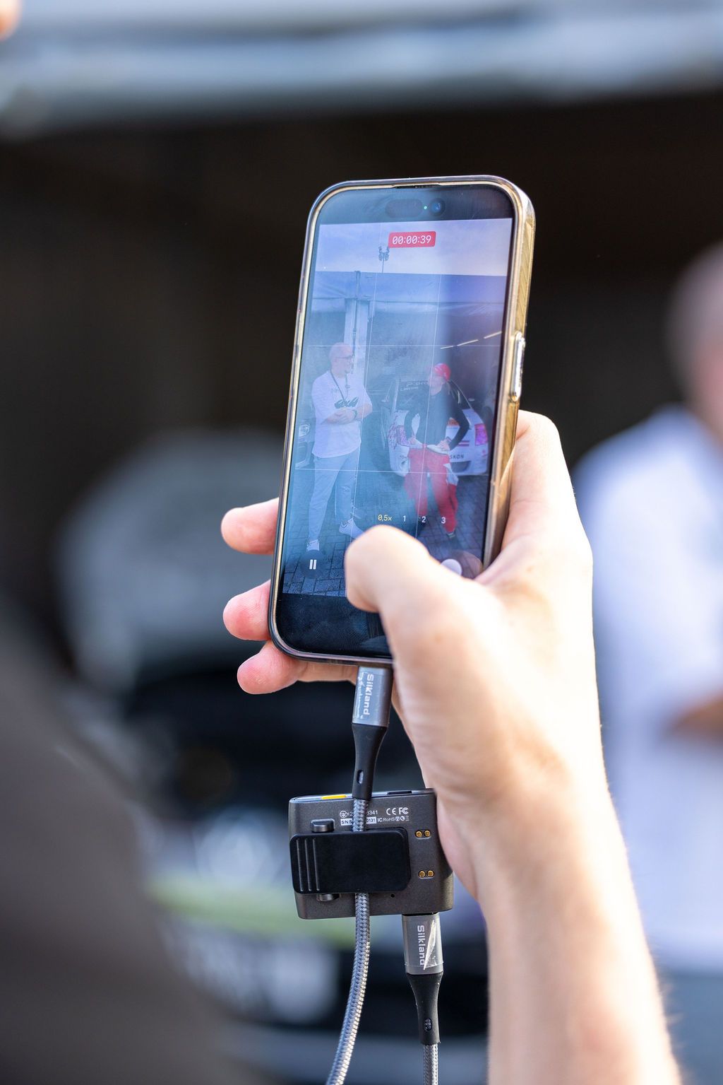 Nahaufnahme von Händen, die ein Smartphone halten, das zur Videoaufnahme auf einem Stabilisierungsgimbal befestigt ist.