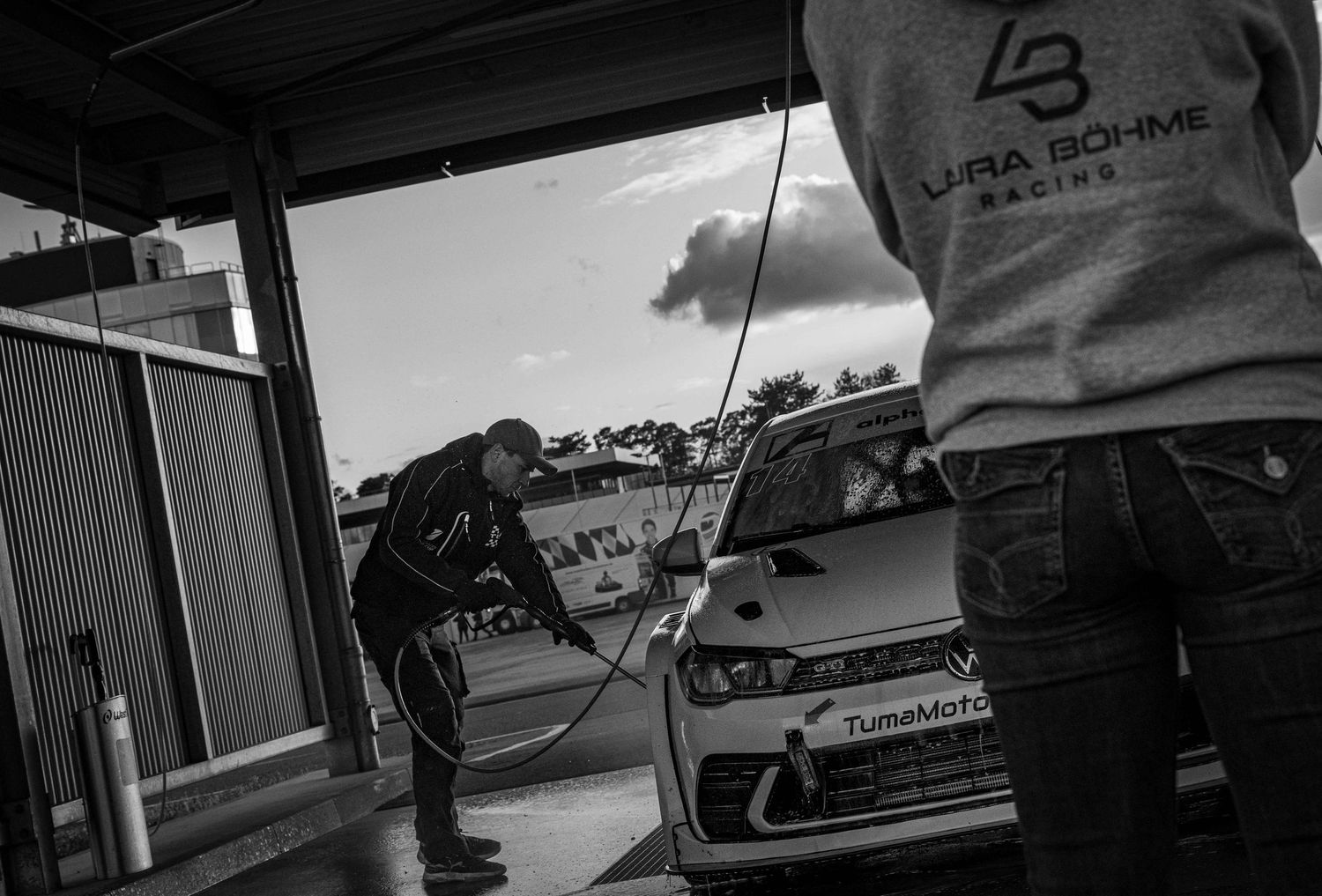 Black and white photo of mechanics servicing a race car at Laura Bohme Racing pit garage.