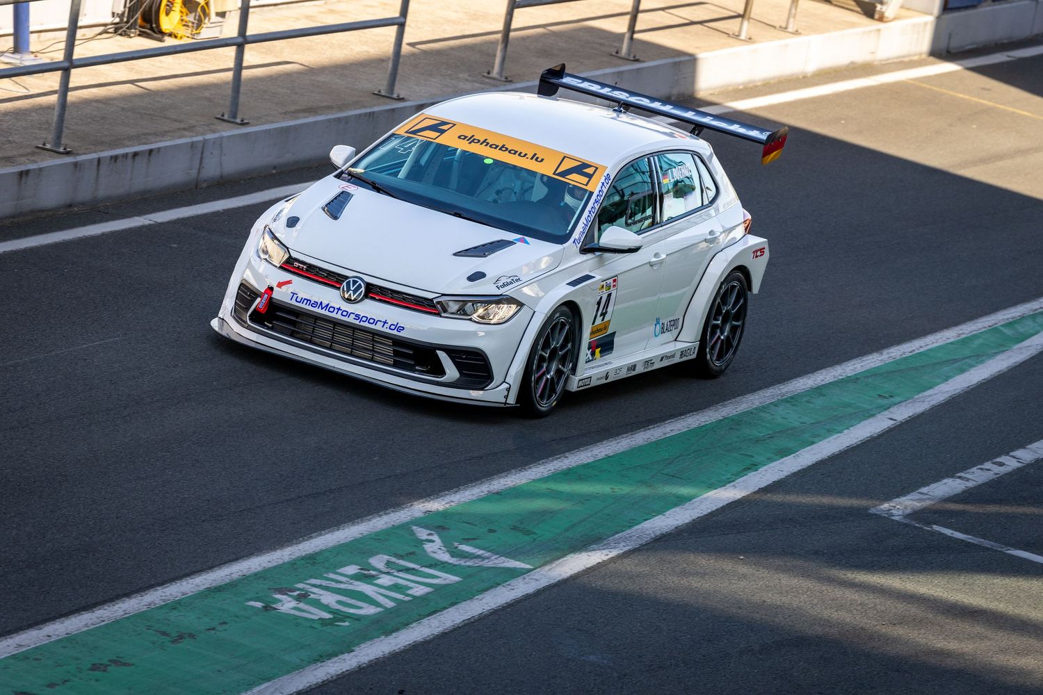 White Volkswagen TCR race car navigating a circuit corner during a motorsport competition event.
