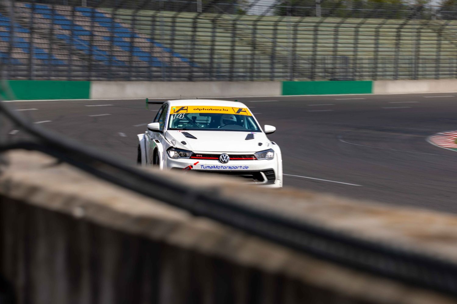 White Volkswagen racing car competing on a circuit track during a motorsport event.
