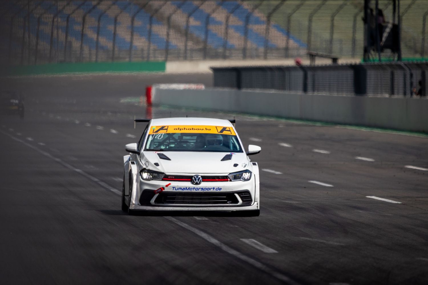 White Volkswagen racing car competing on a professional circuit track during a motorsport event.