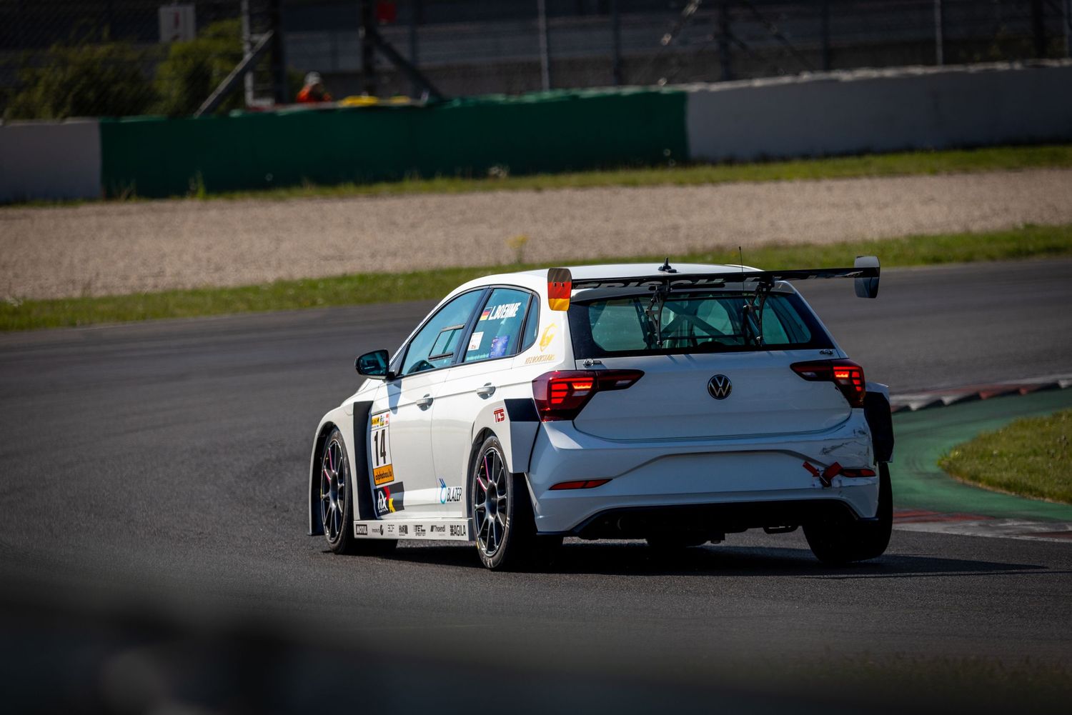 White VW racing car with spoiler on a track circuit during a motorsport competition event.