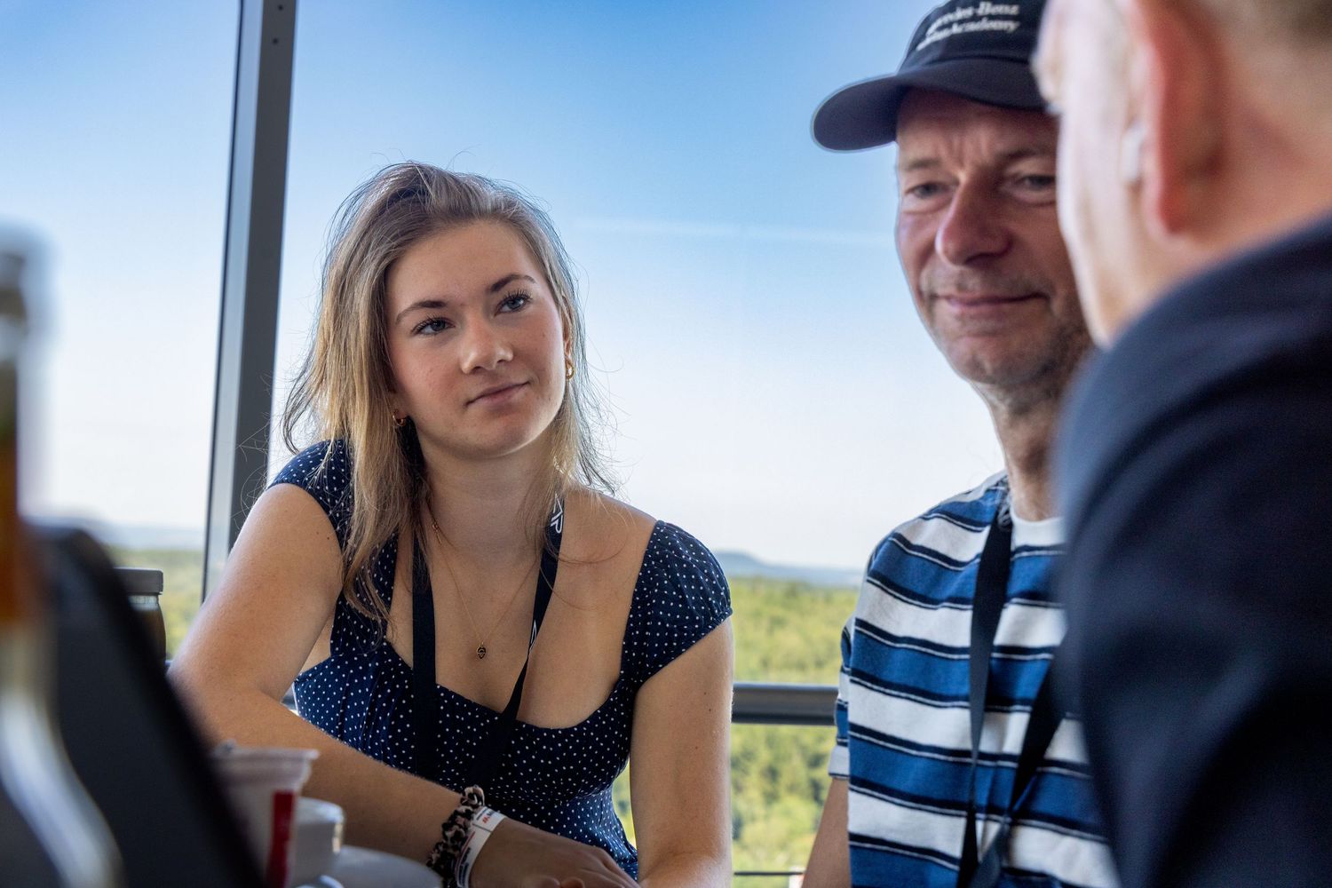 Young woman and man in striped shirt having a conversation at an indoor venue with scenic views.