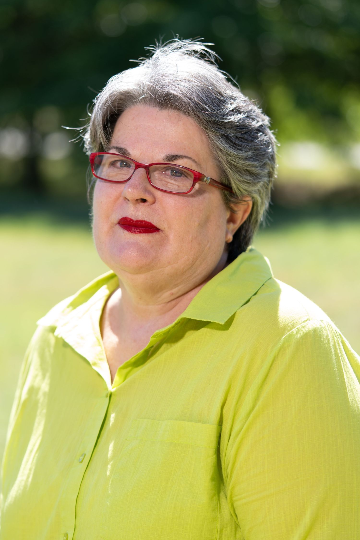 Cheerful outdoor portrait in bright yellow attire against a sunny garden background.