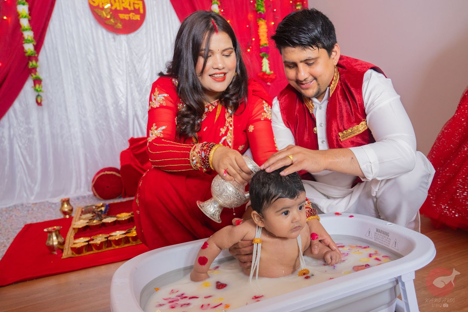 Cultural celebration with participants in red and white attire around table.