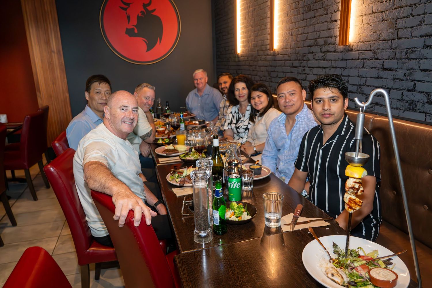 Group dining together at restaurant table with drinks and plates of food.
