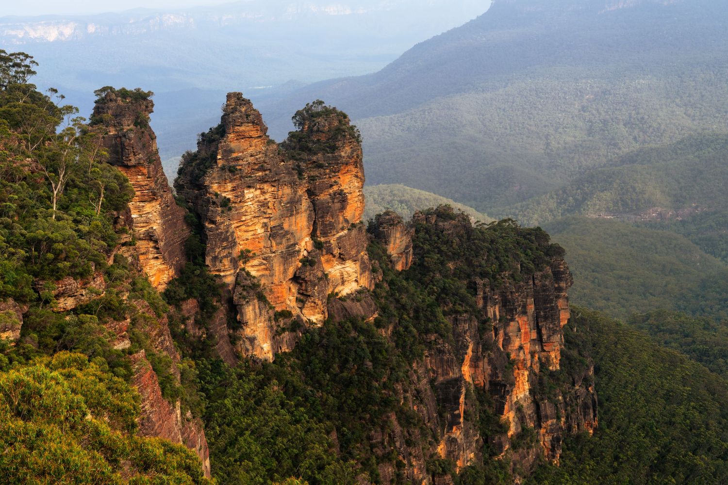 The iconic Three Sisters rock formation stands majestically in the Blue Mountains of Australia at sunset.
