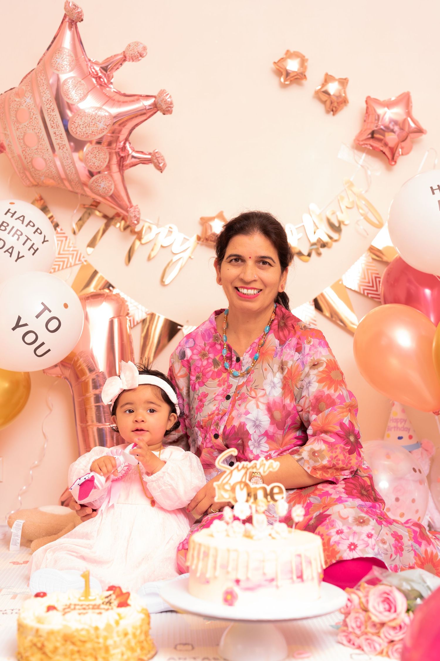 Birthday celebration setup with pink and gold balloons, star decorations, and white cake.
