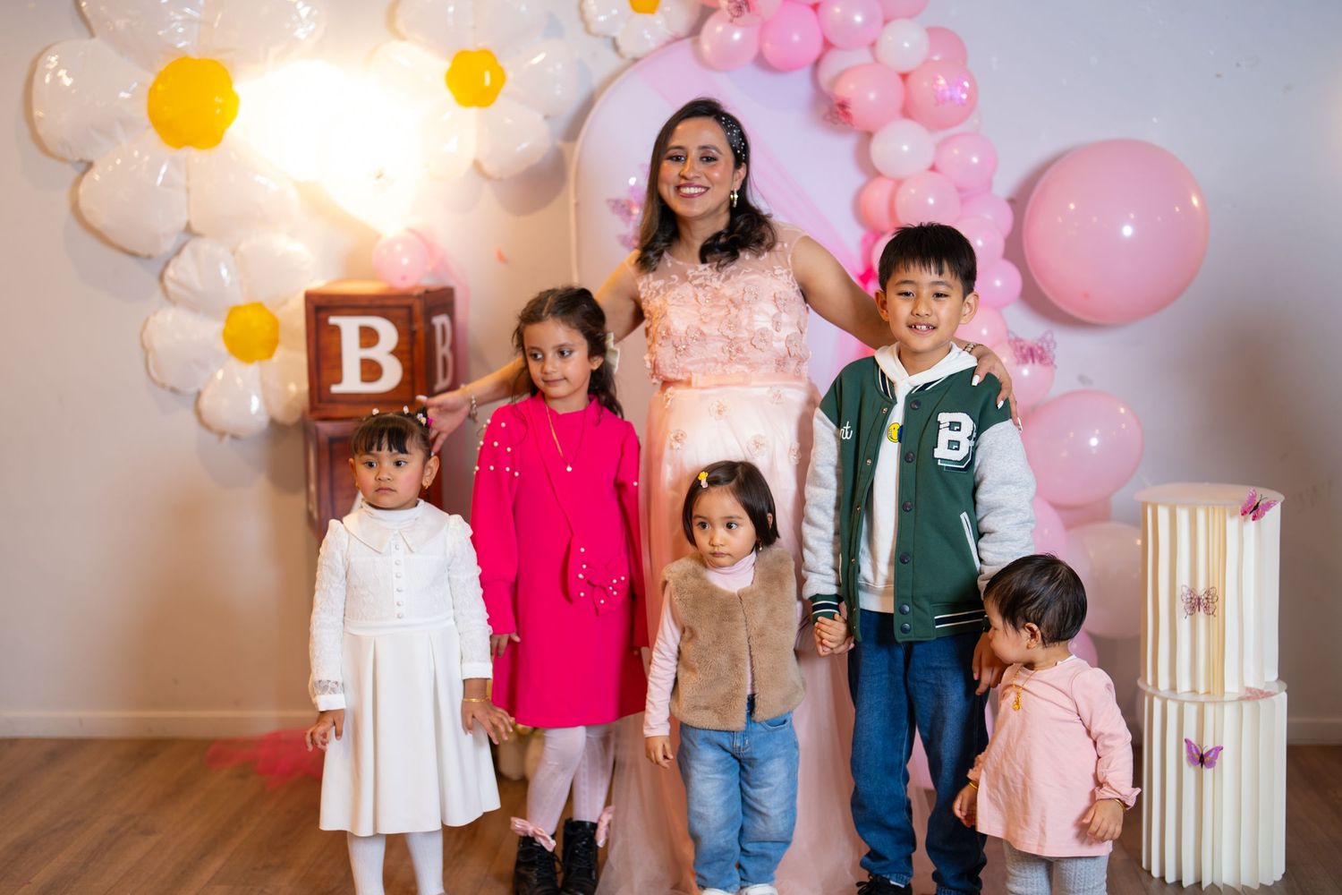 Small group poses in front of balloon arch and decorative blocks at a baby shower.