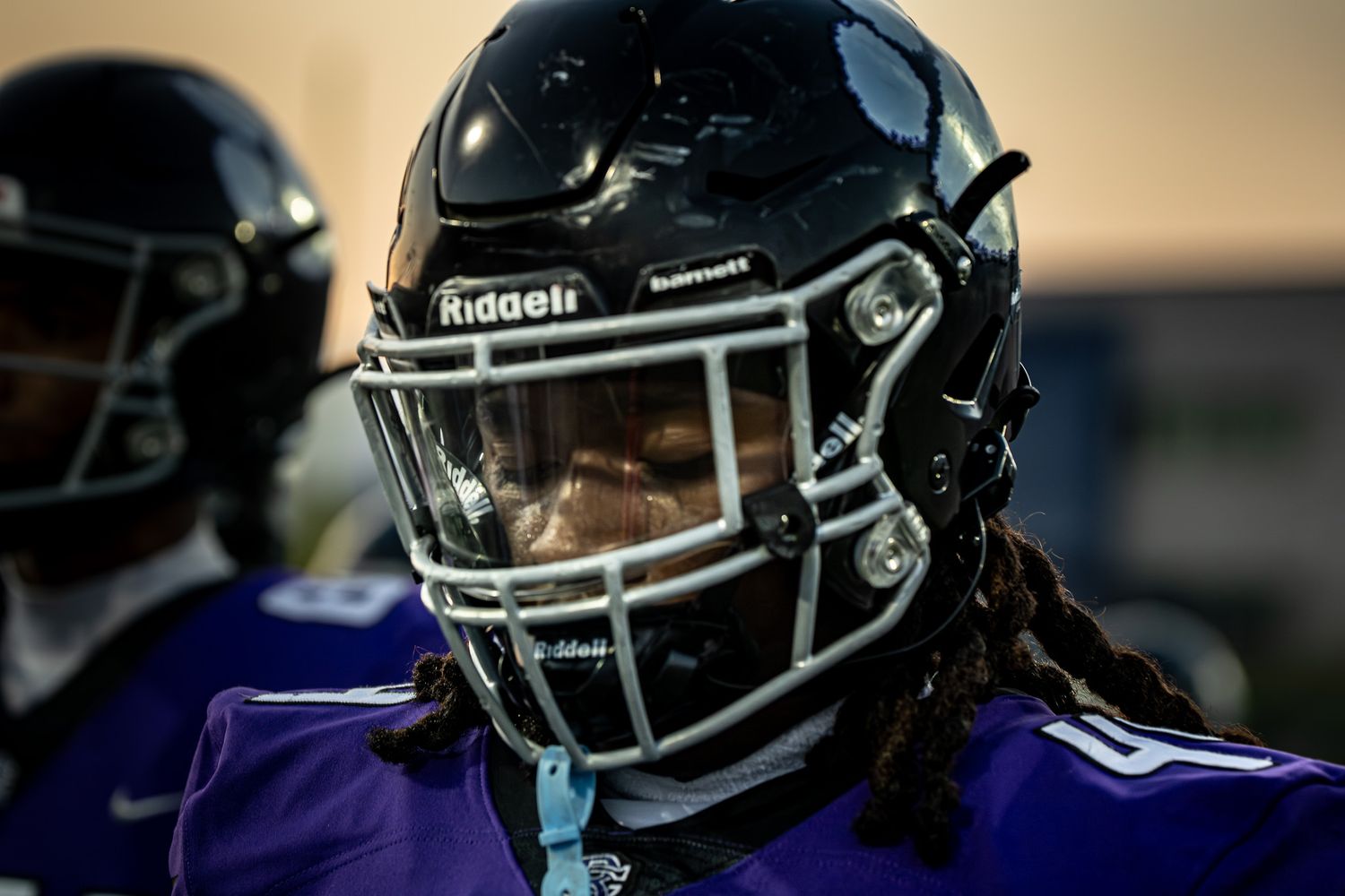 Football player portrait under stadium lights wearing helmet.