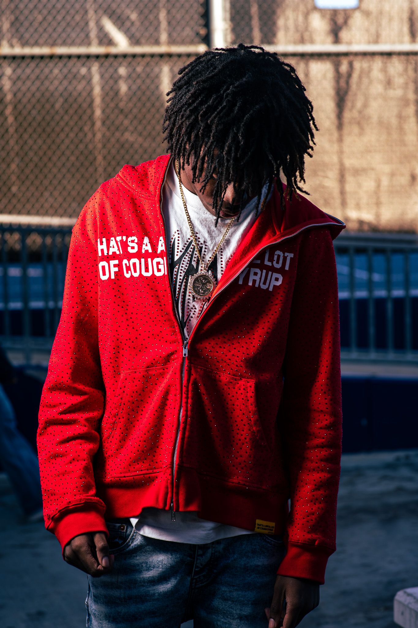 Lifestyle portrait of a young man in an urban setting wearing a red jacket, captured with natural light and candid style.