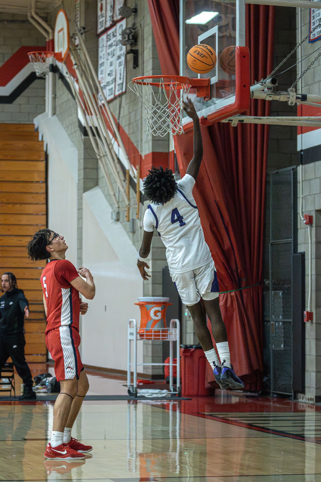 High school basketball player attempting a layup during live game action.
