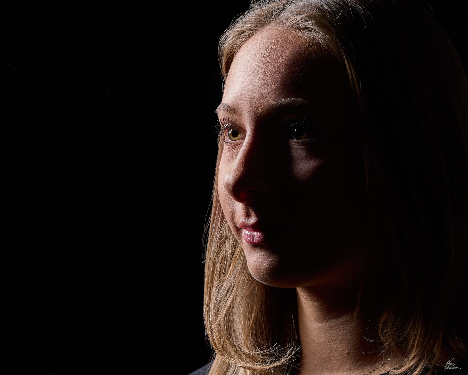 Artistic side-lit portrait with dramatic shadows and soft lighting.