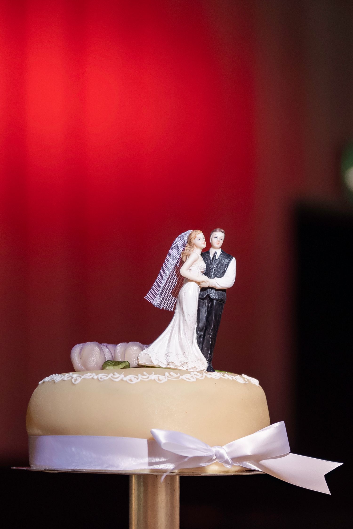 Wedding cake topper figurines against red background in sequence.