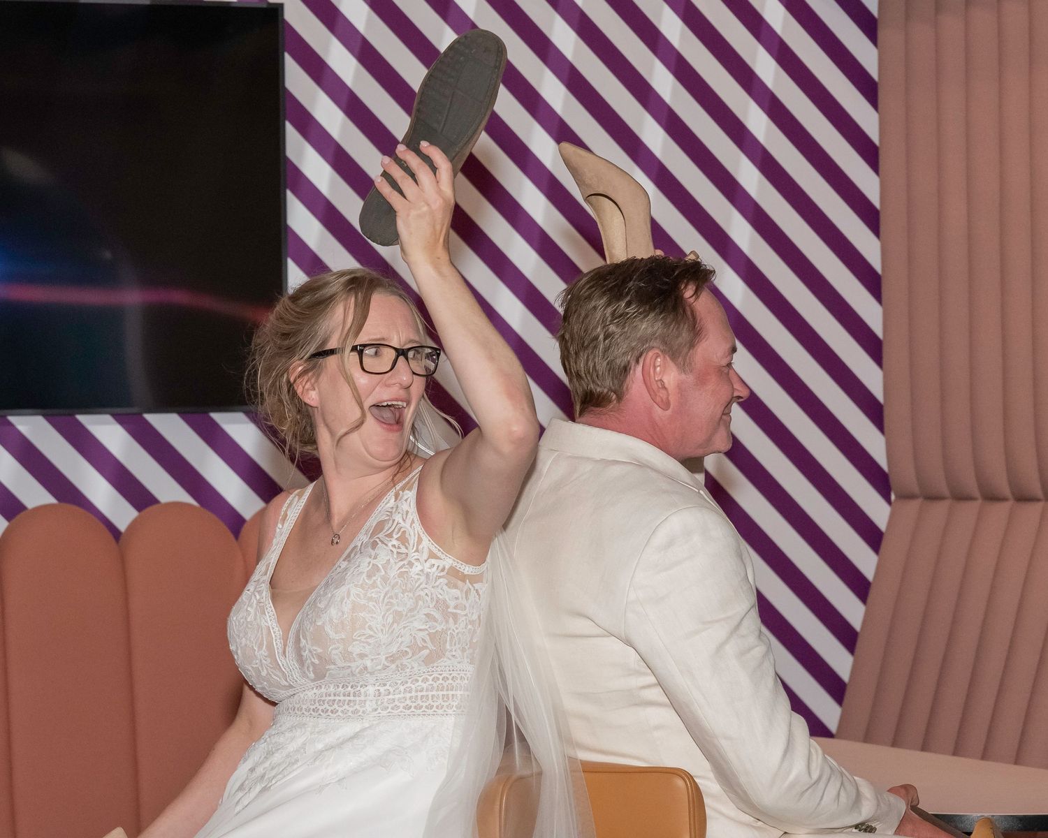 Wedding couple dancing together under purple striped decor at their reception celebration.