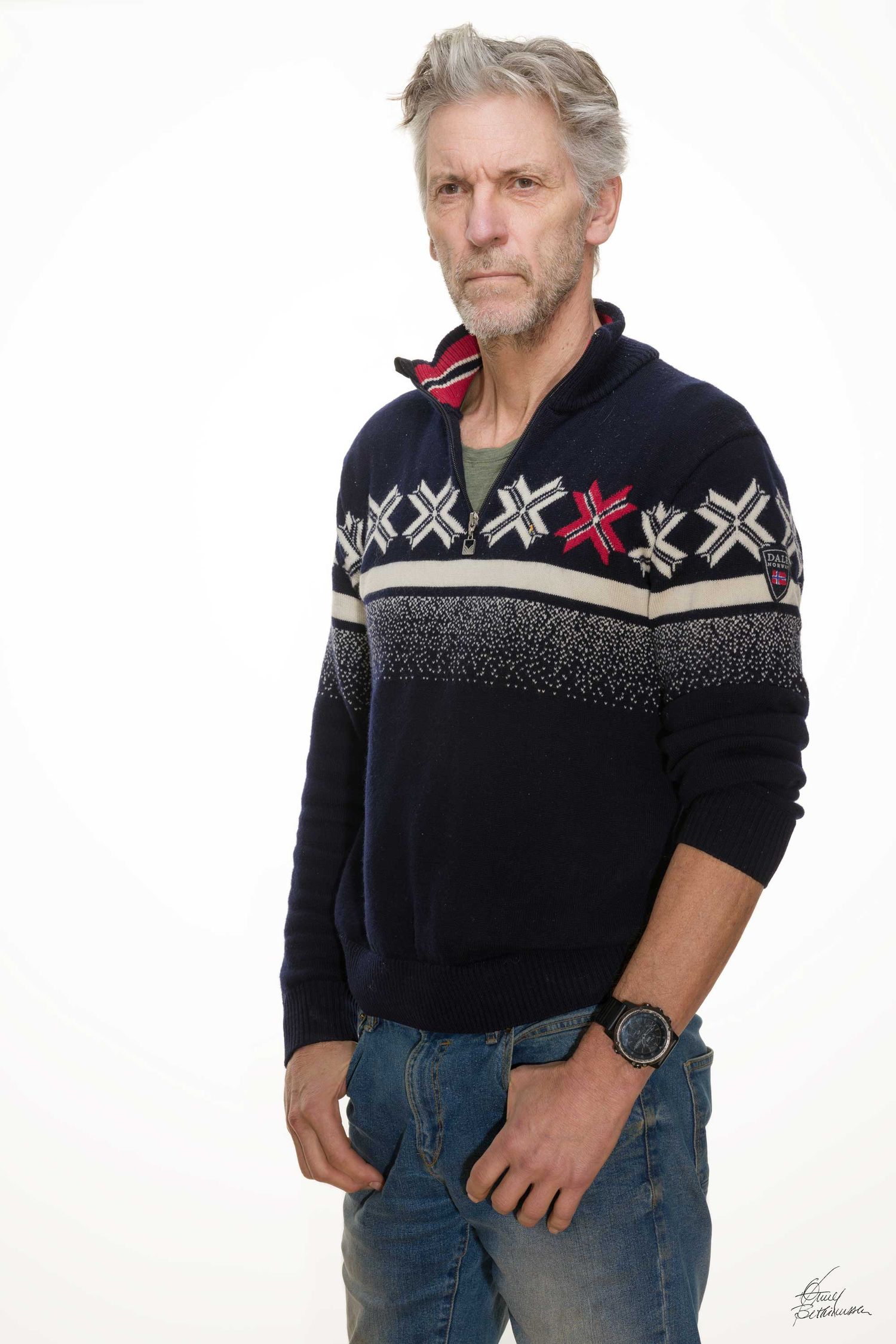 Person wearing a navy Nordic pattern sweater and jeans poses against white background.