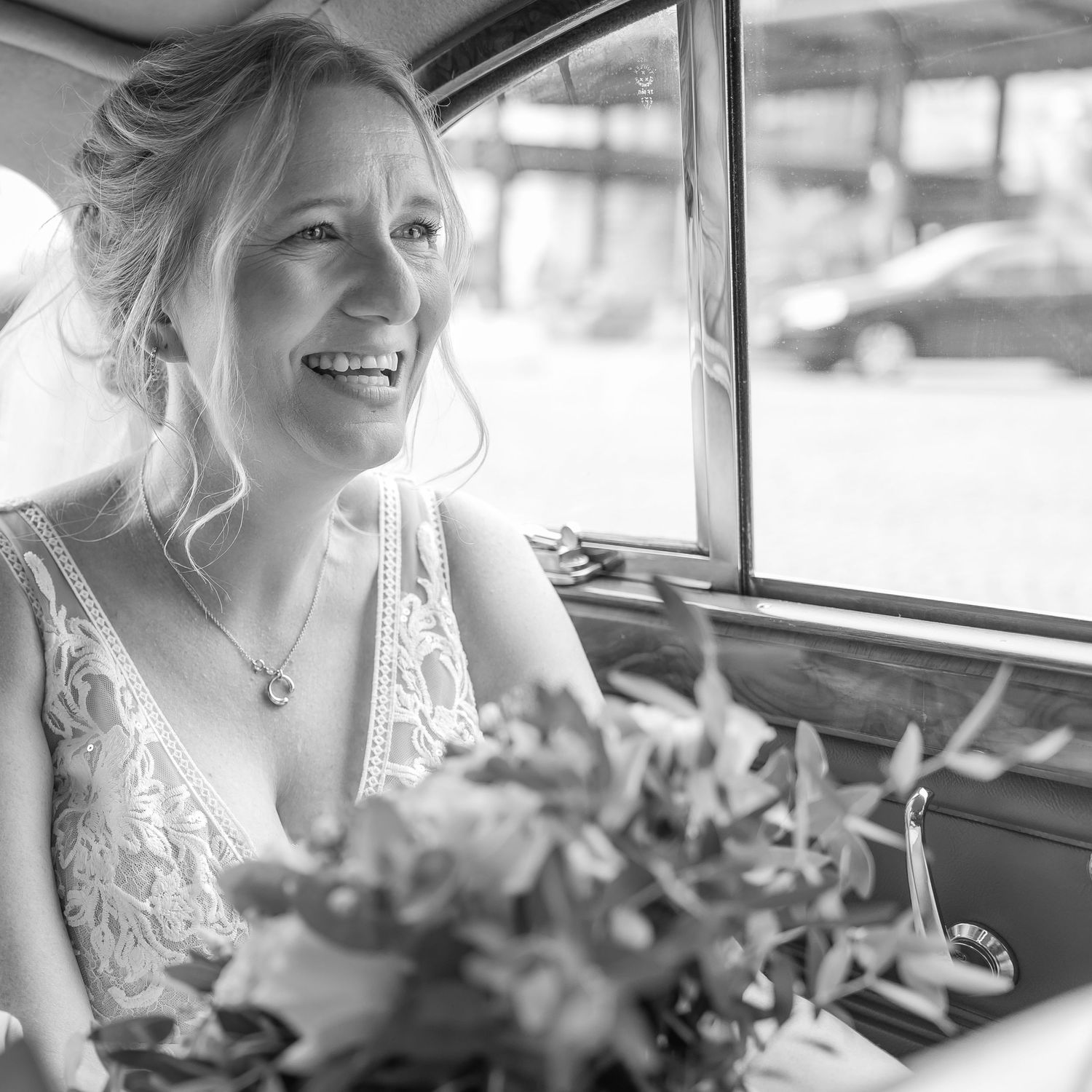 Wedding attire with intricate lace details seen through a vintage car window.