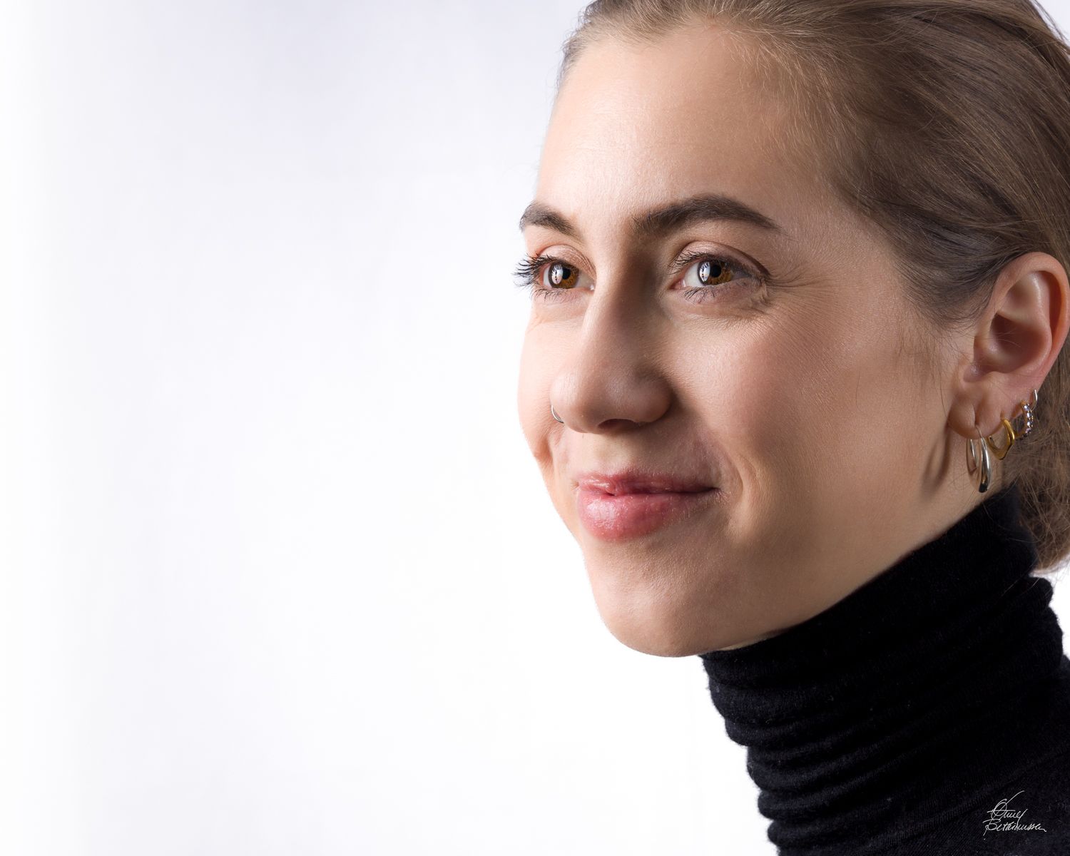Clean studio portrait against white background showing gentle smile and black turtleneck.