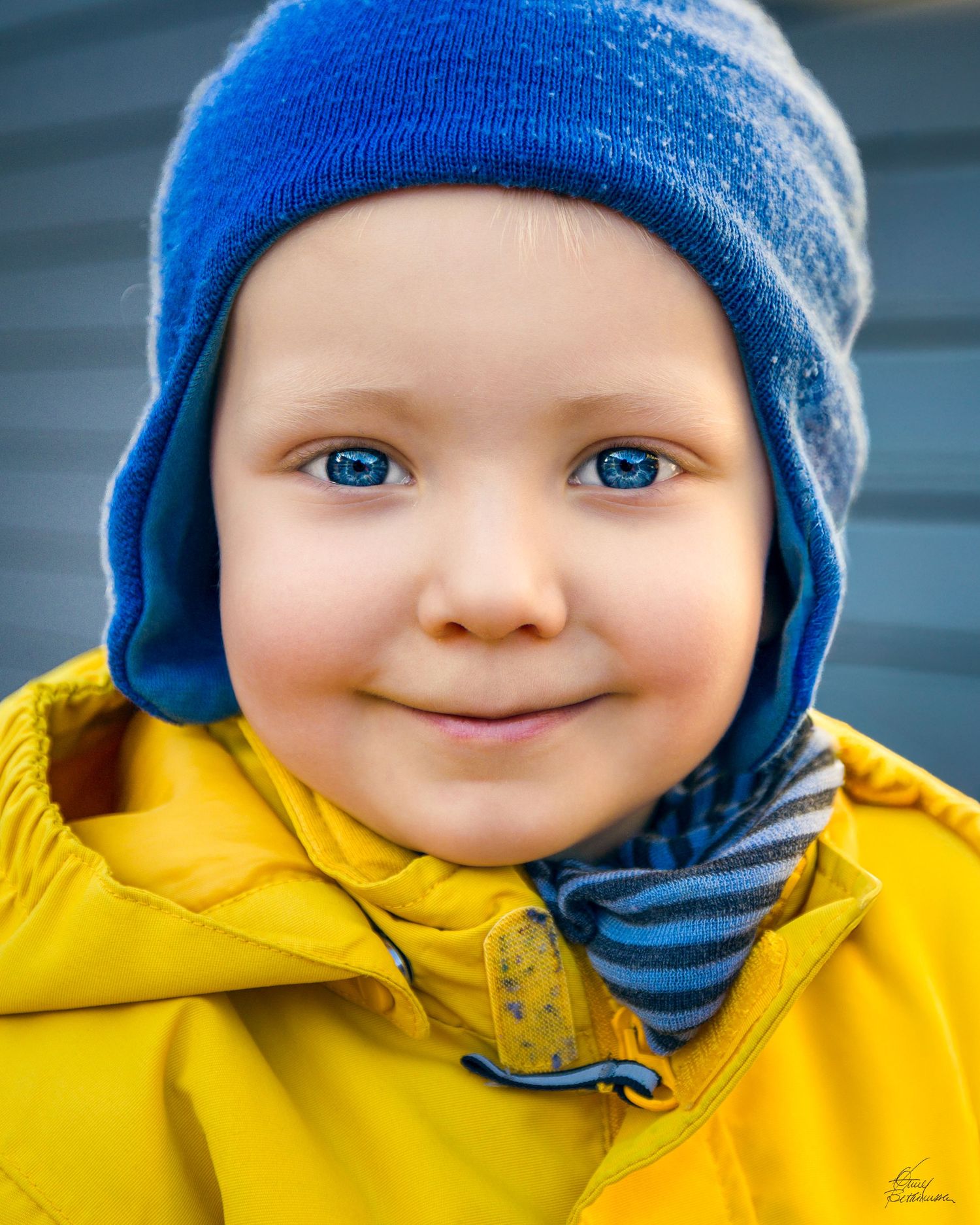 Close-up series of a child in a blue winter hat and yellow coat showing cheerful expressions.